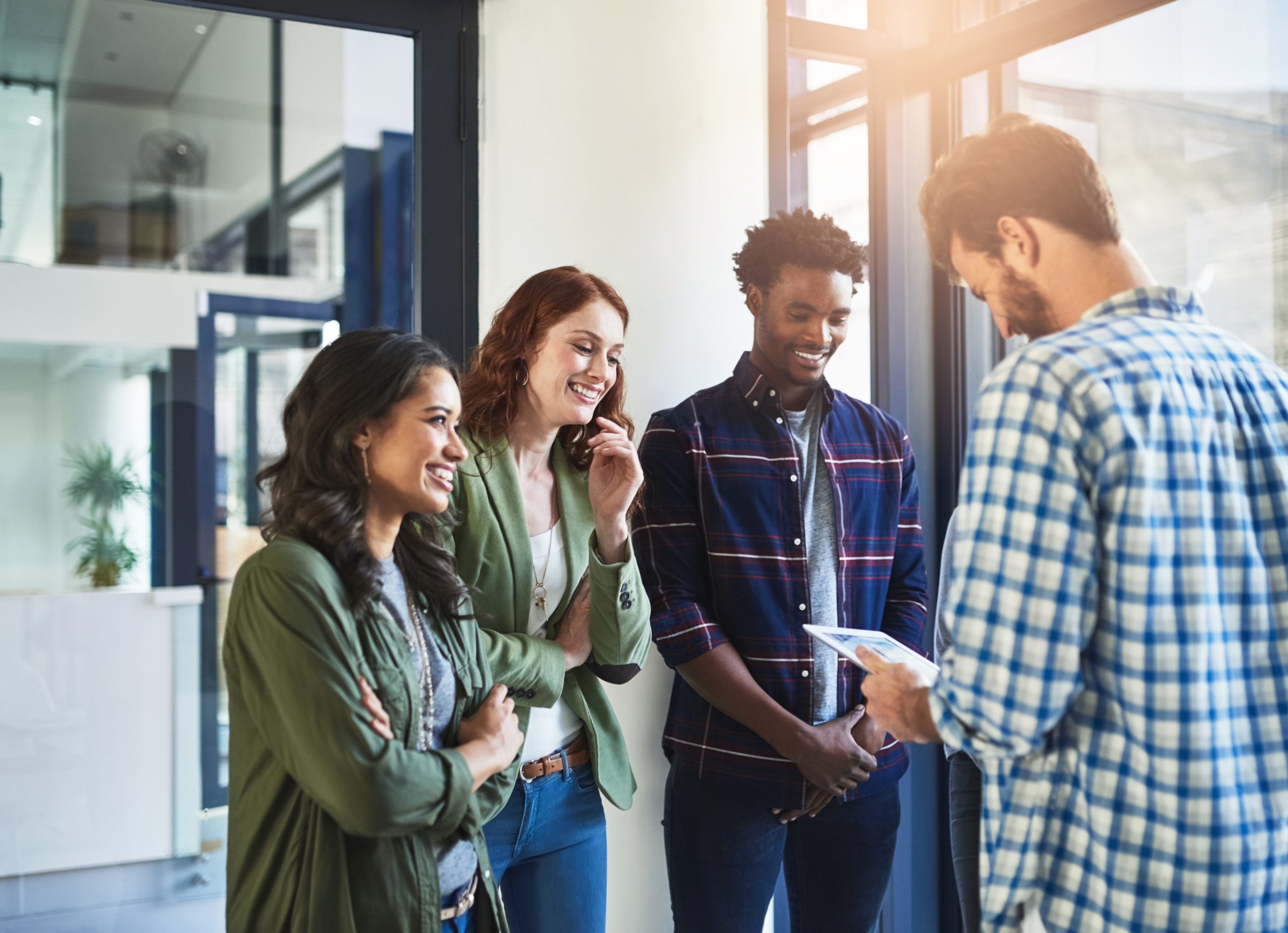 grupo de jovens adultos em ambiente profissional conversando em pé