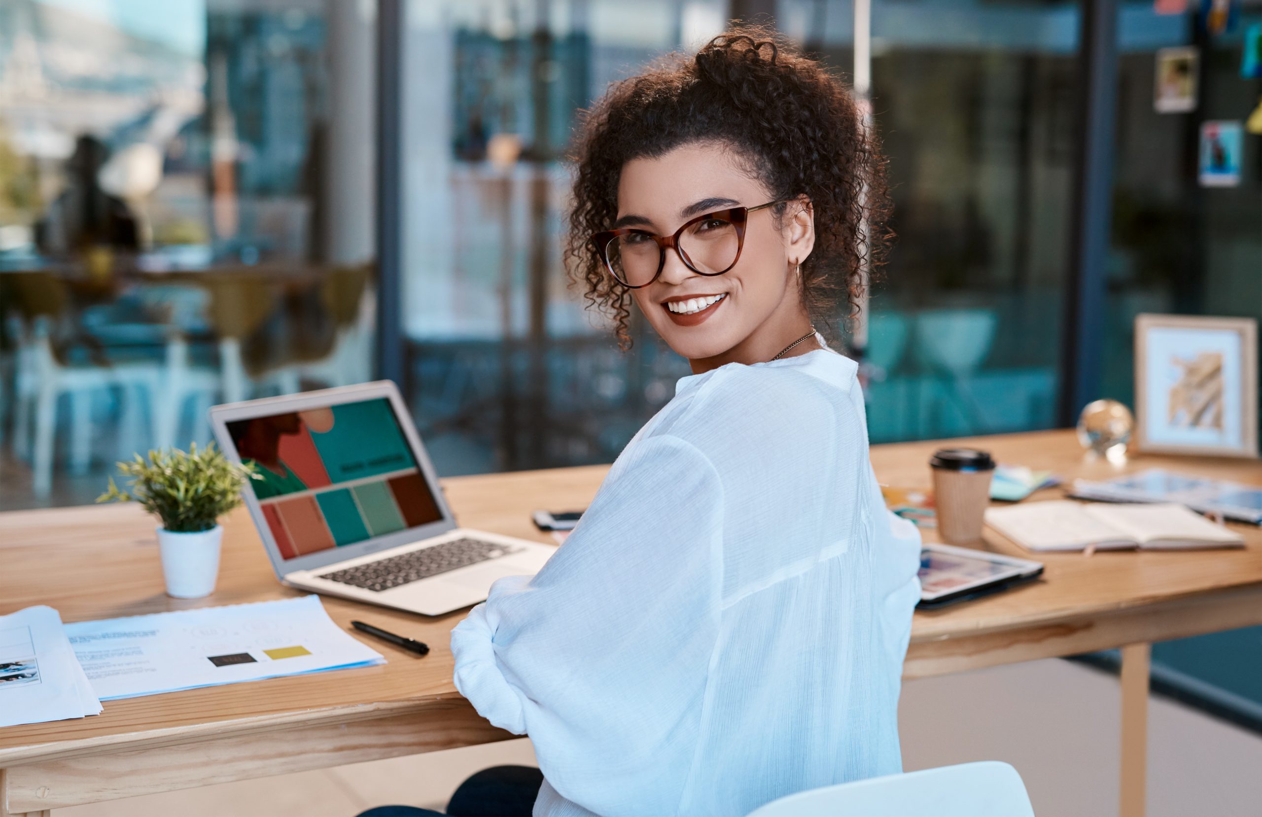 muher sentada em um escritório sorrindo em frente ao computador