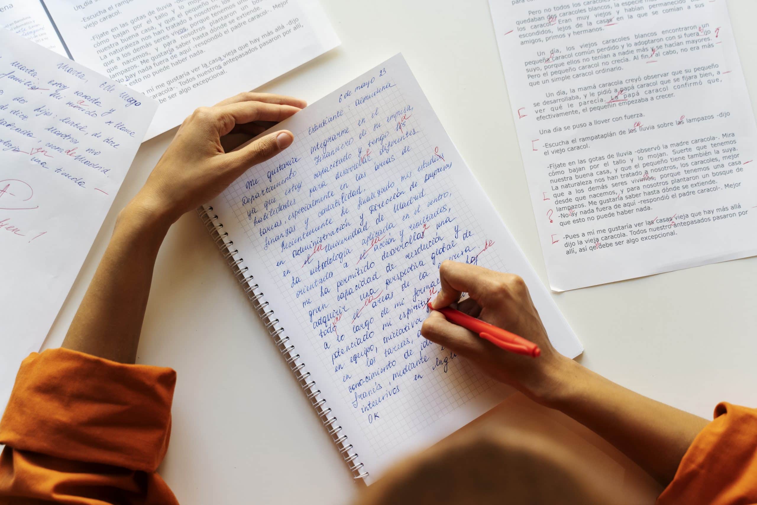 maos femininas escrevendo redação em um caderno