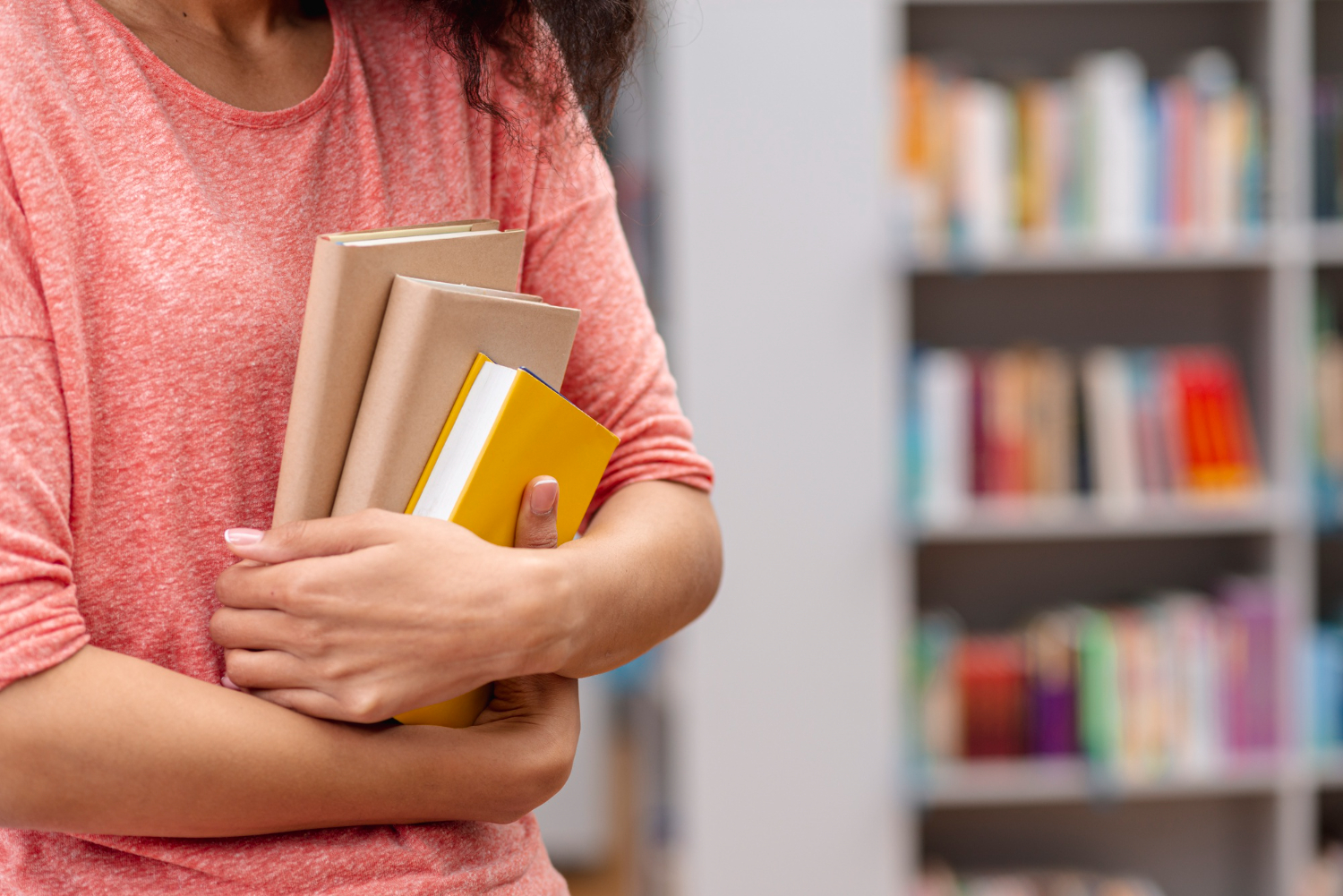 mulher segurando livros na biblioteca