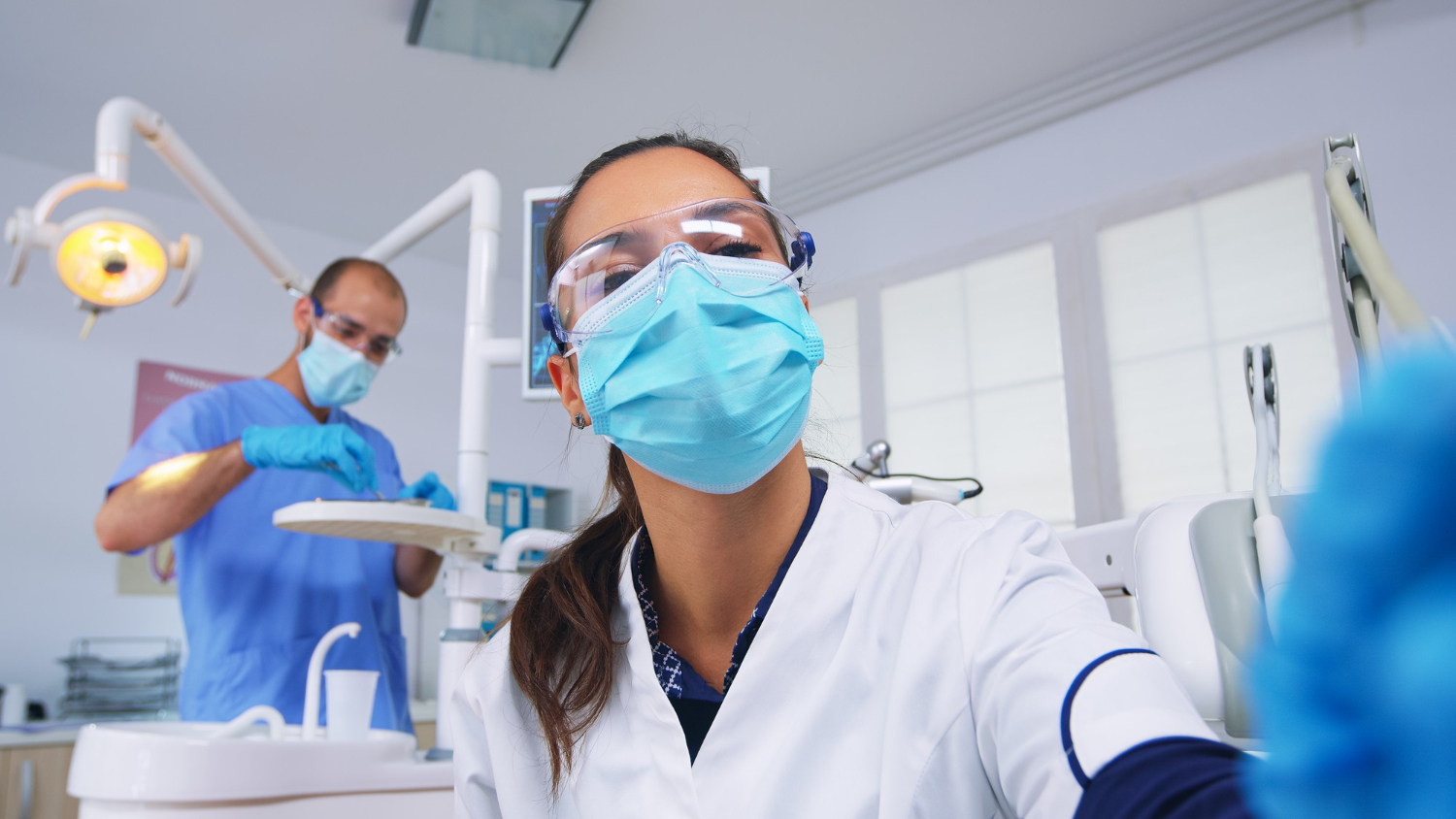 Mulher com mascara e uniforme, dentro da clinica de odontologia.