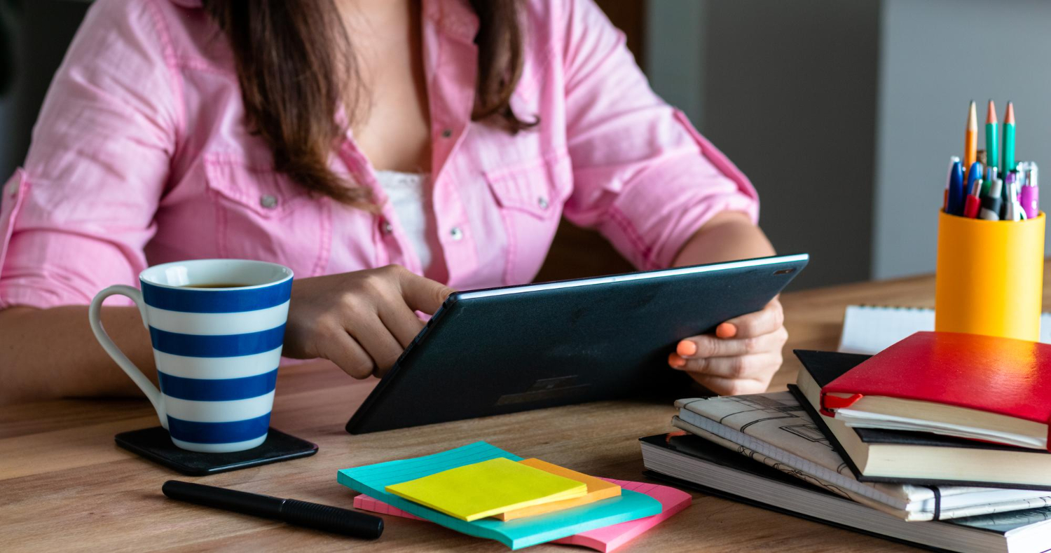 Mulher em frente a mesa, com um tablet na mão fazendo mapas mentais.