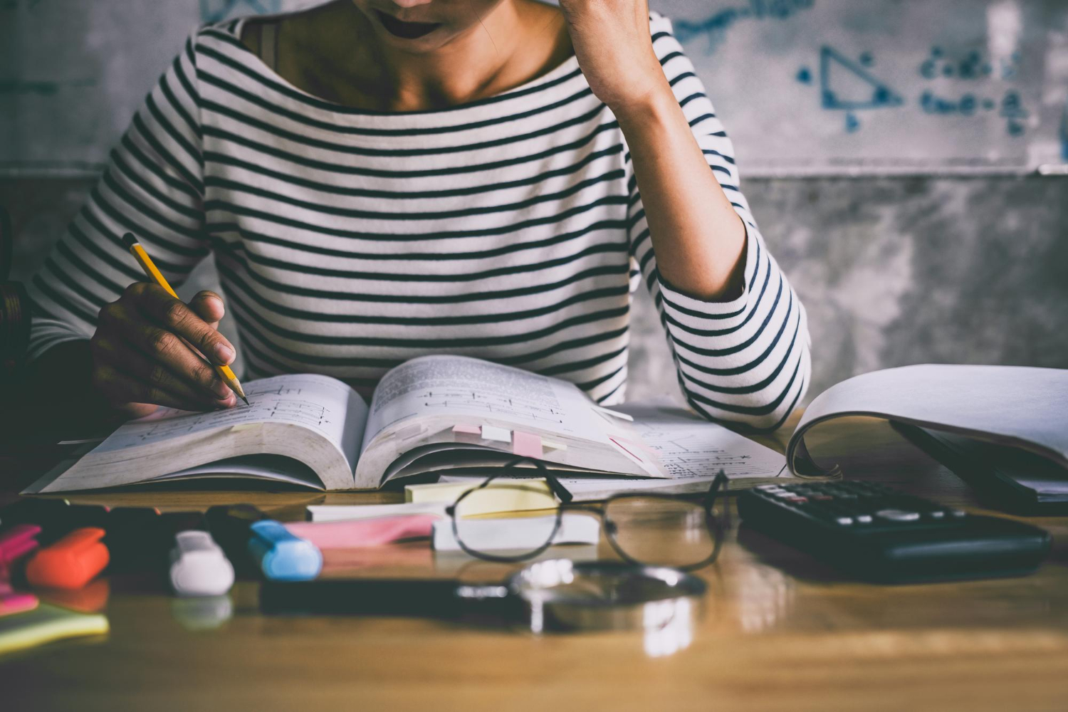 mulher com cadernos e materiais de estudos abertos sobre a mesa